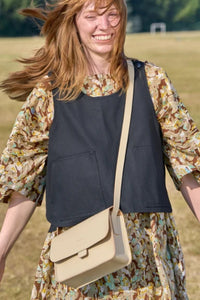 Lifestyle shot of the UK-made Kate Sheridan Putty Tab Bag. A minimalist cream leather crossbody bag for women.