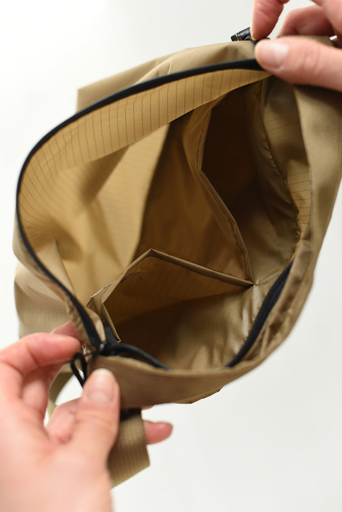 
                  
                    The inside details of a light brown nylon crossbody bag.
                  
                