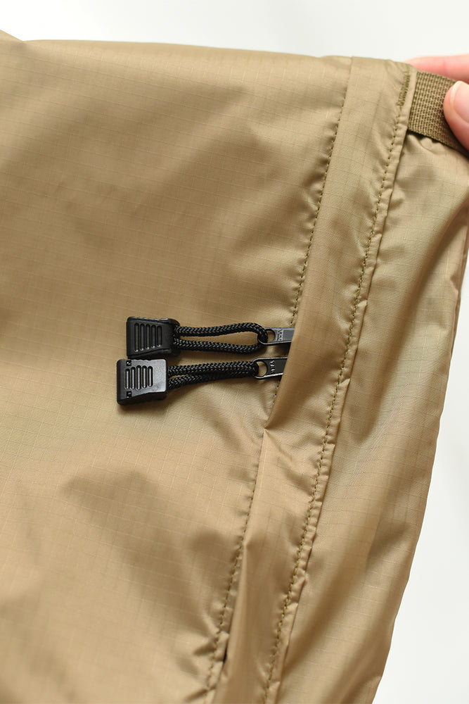 
                  
                    The zipper details of a light brown nylon crossbody bag
                  
                