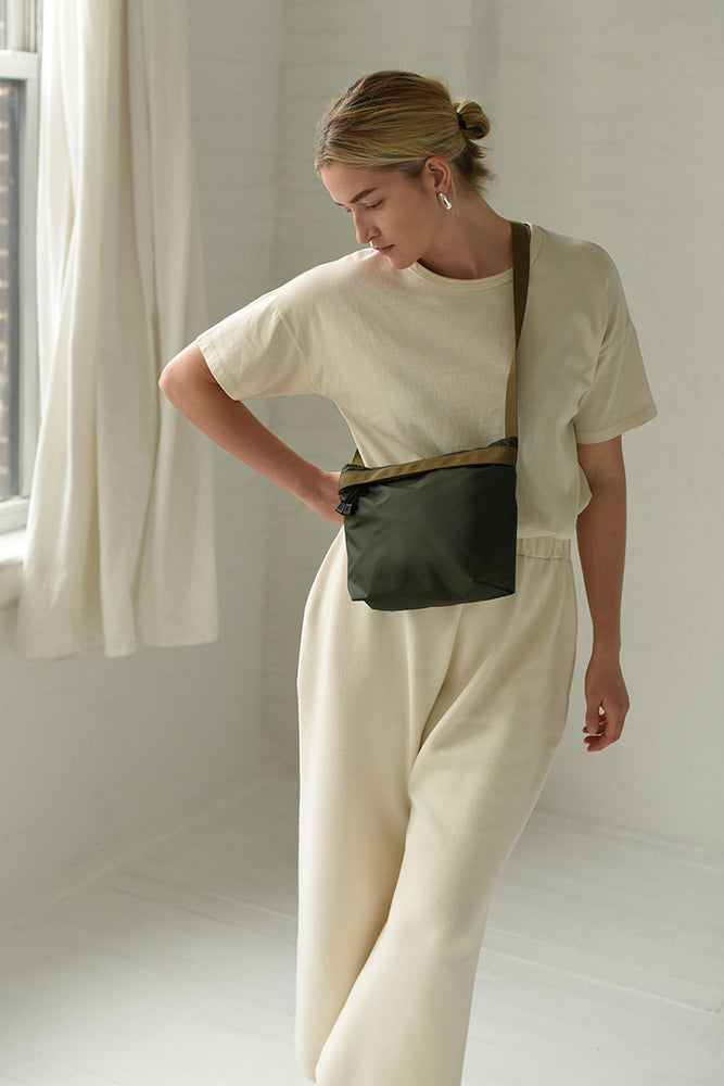 
                  
                    A woman wears a nylon green crossbody waterproof bag
                  
                