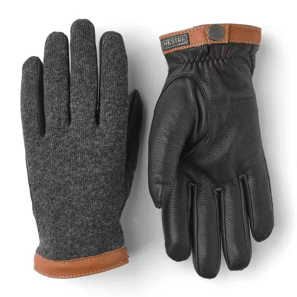 A pair of men's gloves with a charcoal wool jersey backhand and supple black deerskin palm, featuring a brown vegetable tanned goatskin cuff with a press stud.