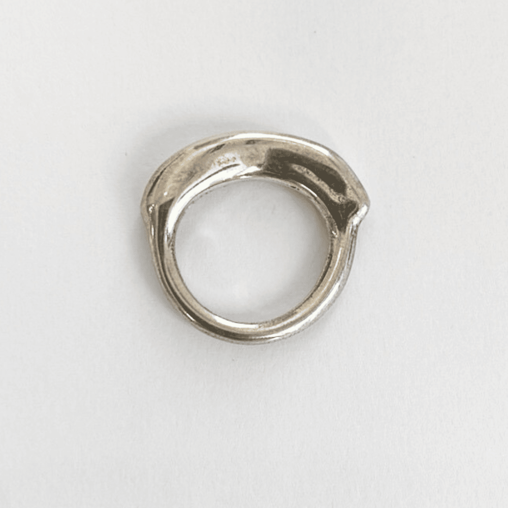 A silver band ring with a thick organic top, viewed from the side, showing the thickness and the band's profile.