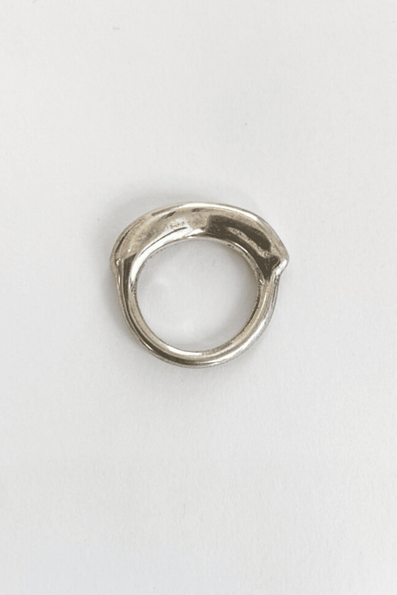 A silver band ring with a thick organic top, viewed from the side, showing the thickness and the band's profile.