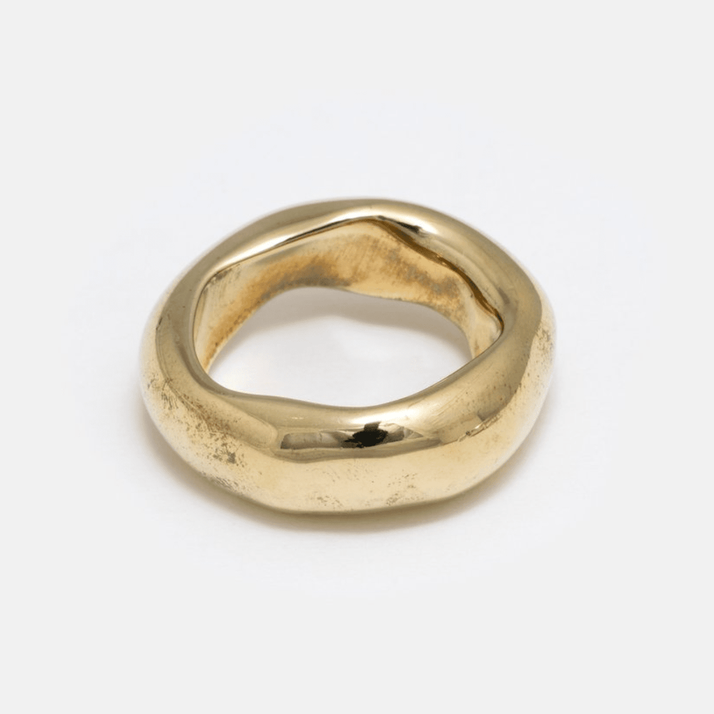 A simple, heavy wide band ring made of brass, with a smooth finish.