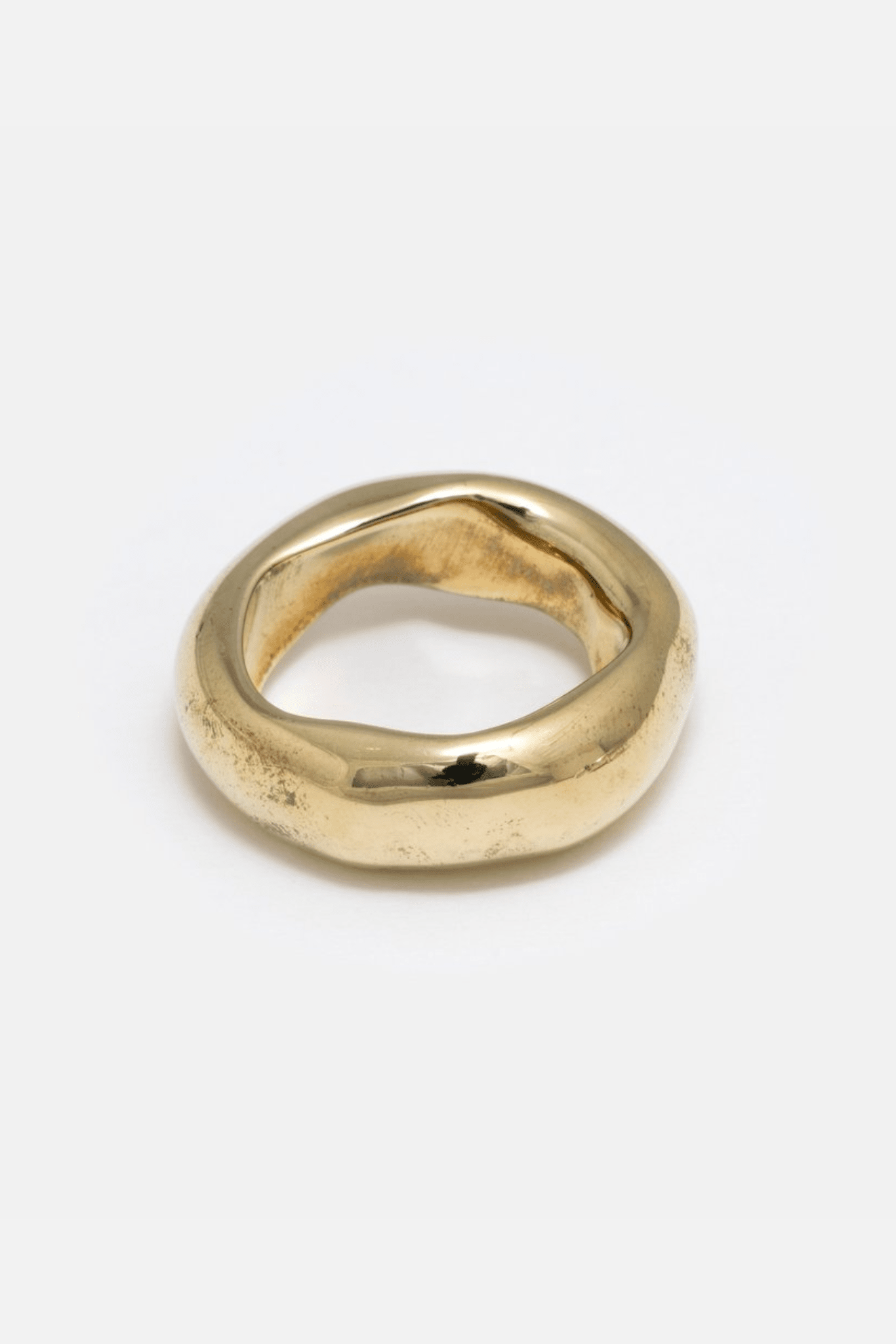A simple, heavy wide band ring made of brass, with a smooth finish.