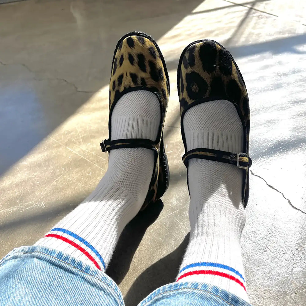 A person wears white striped cotton crew socks with leopard mary jane shoes