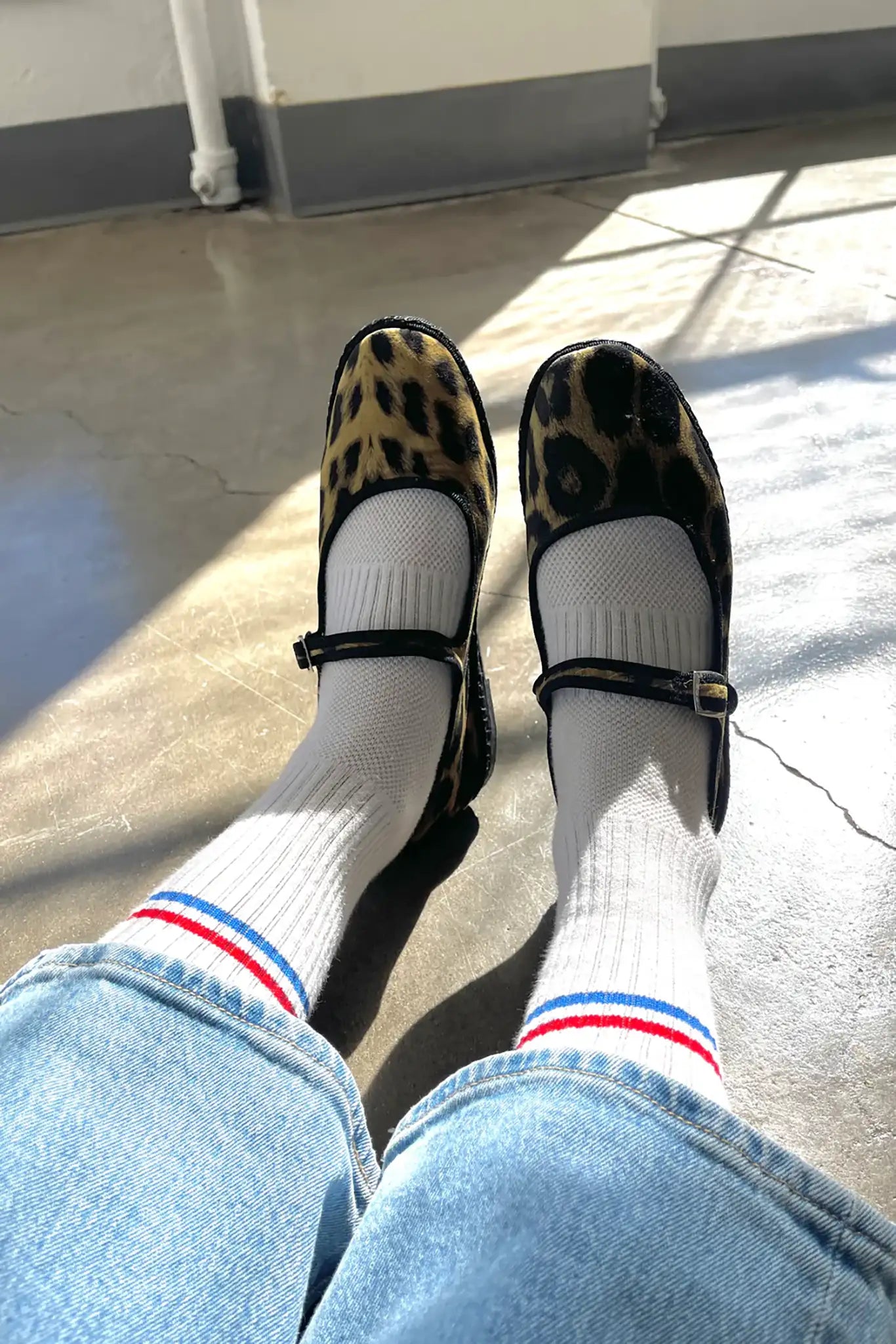 A person wears white striped cotton crew socks with leopard mary jane shoes