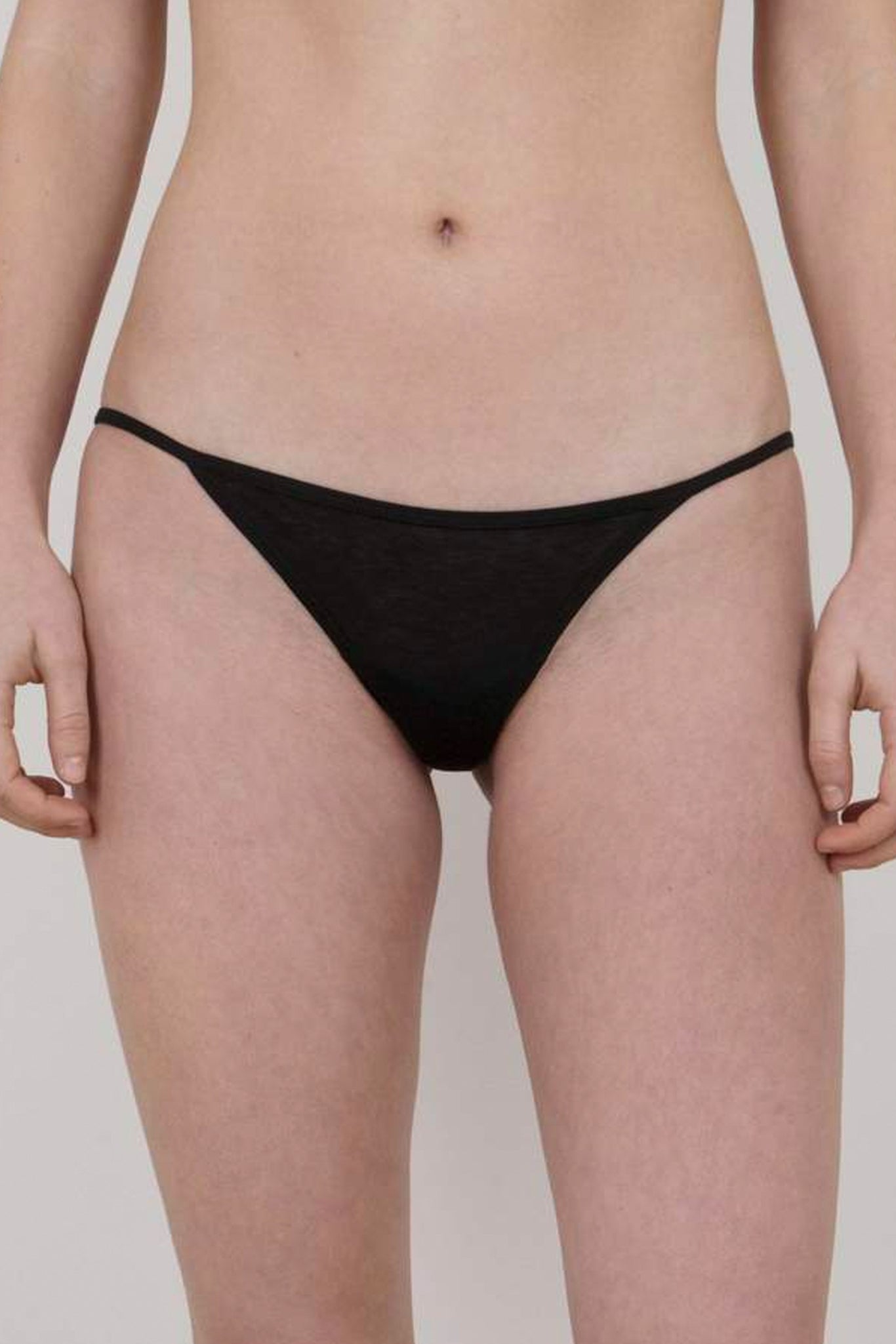 This image features a pair of stylish, low-rise string bikini panties, designed with a minimalist aesthetic in a sleek black color. The underwear is crafted from lightweight and sheer cotton fabric, enhancing comfort and breathability.