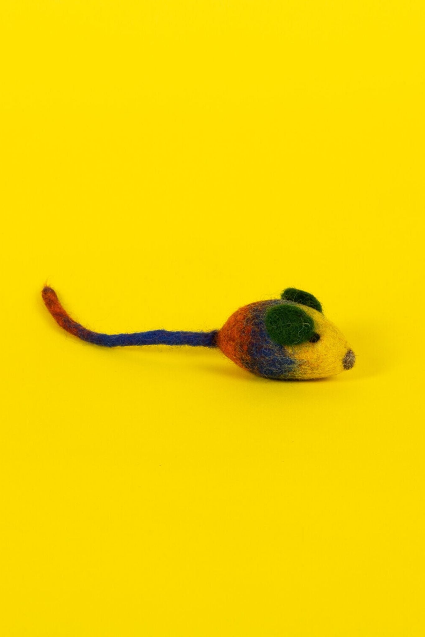 A felted wool cat toy designed to look like a mouse, with red and orange accents on a yellow background.