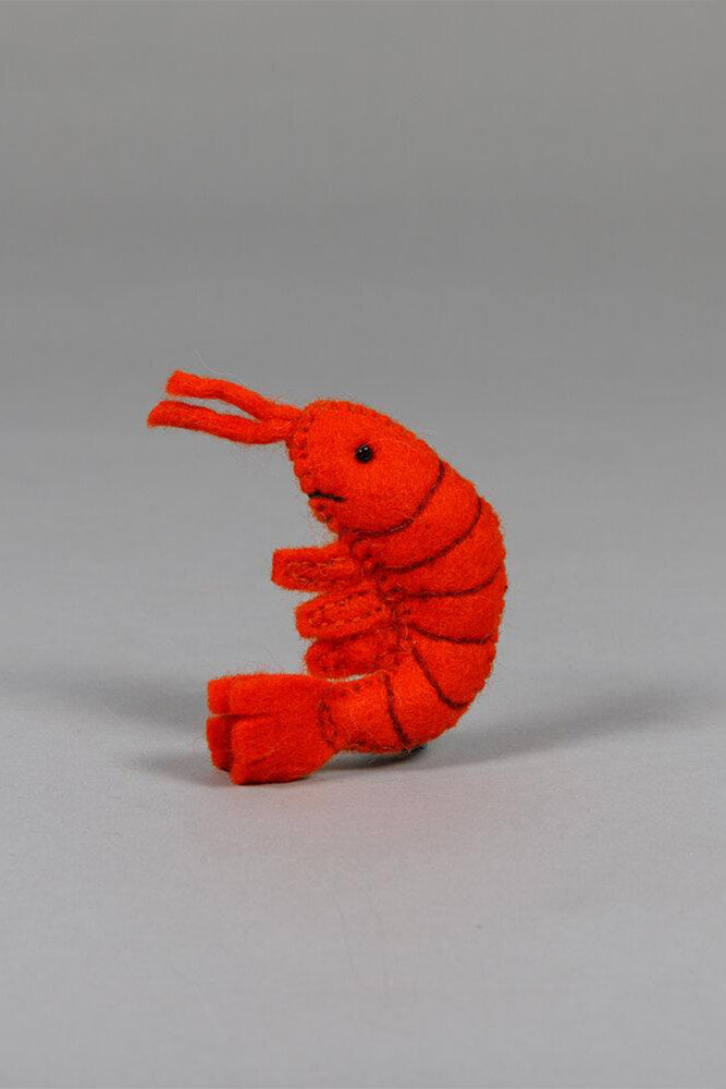 A red felted shrimp cat toy sitting on a gray background.