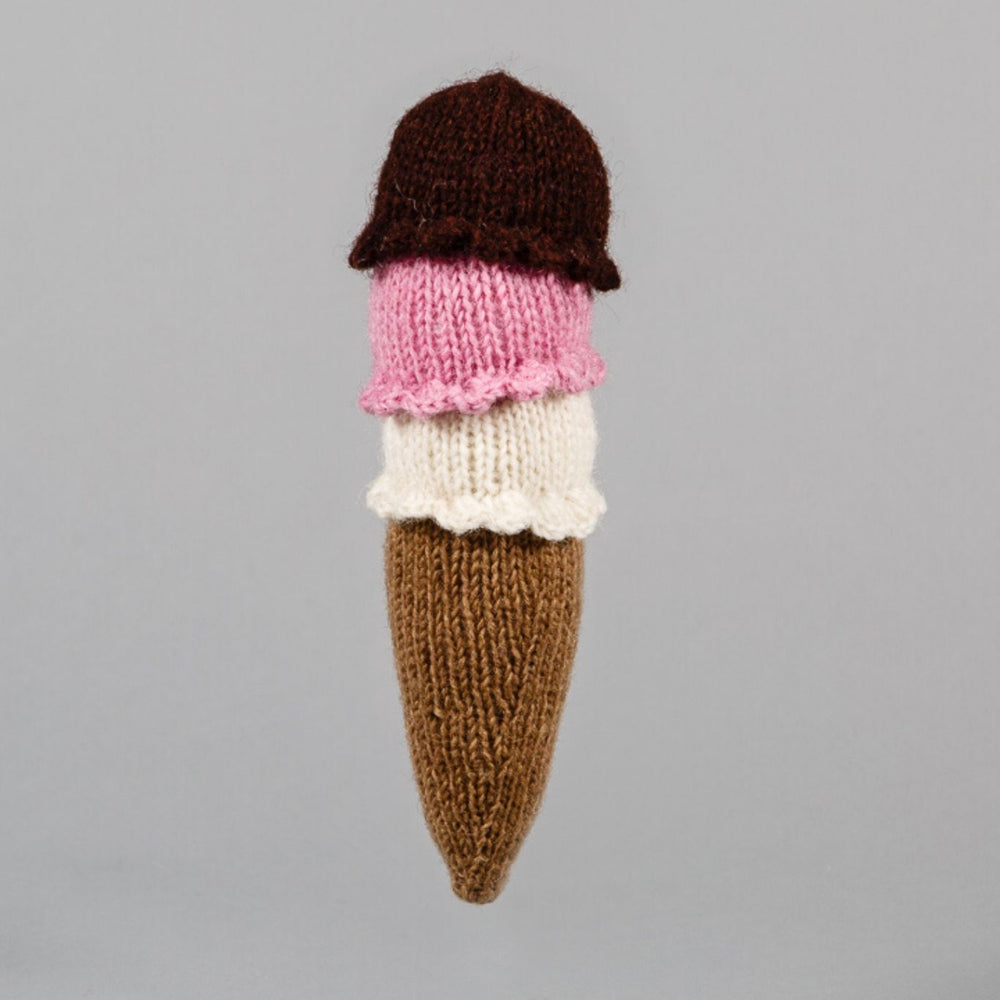 A hand knit dog toy shaped like an ice cream cone with brown, pink, and white colors.