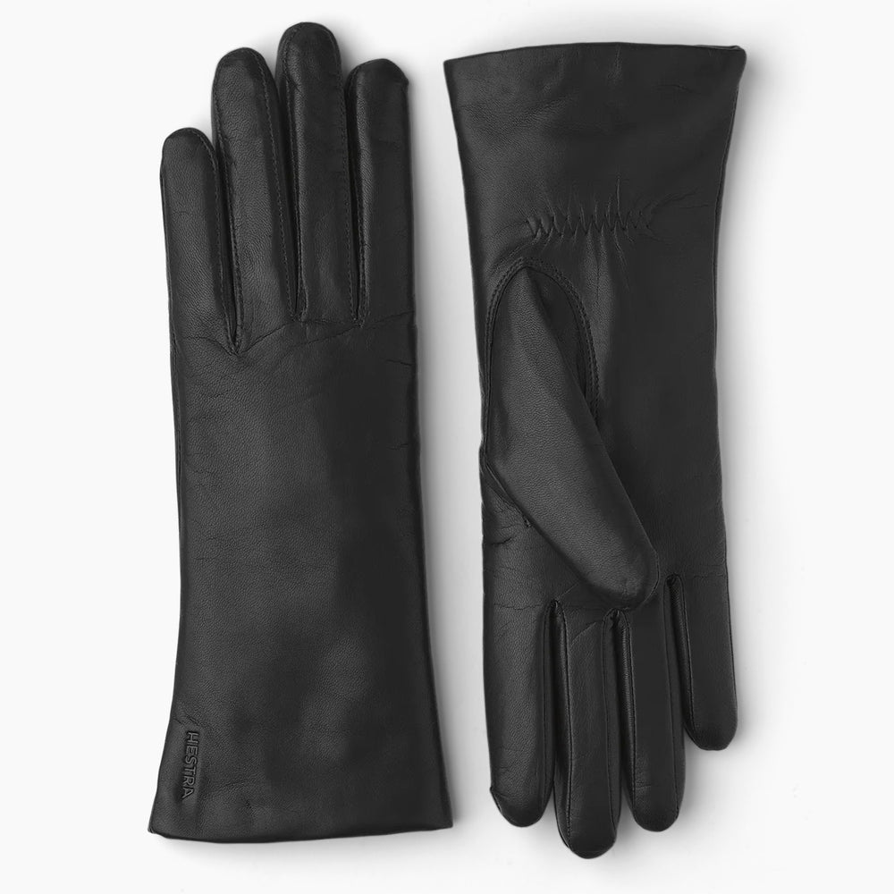 Women's black leather gloves laying flat on a grey background