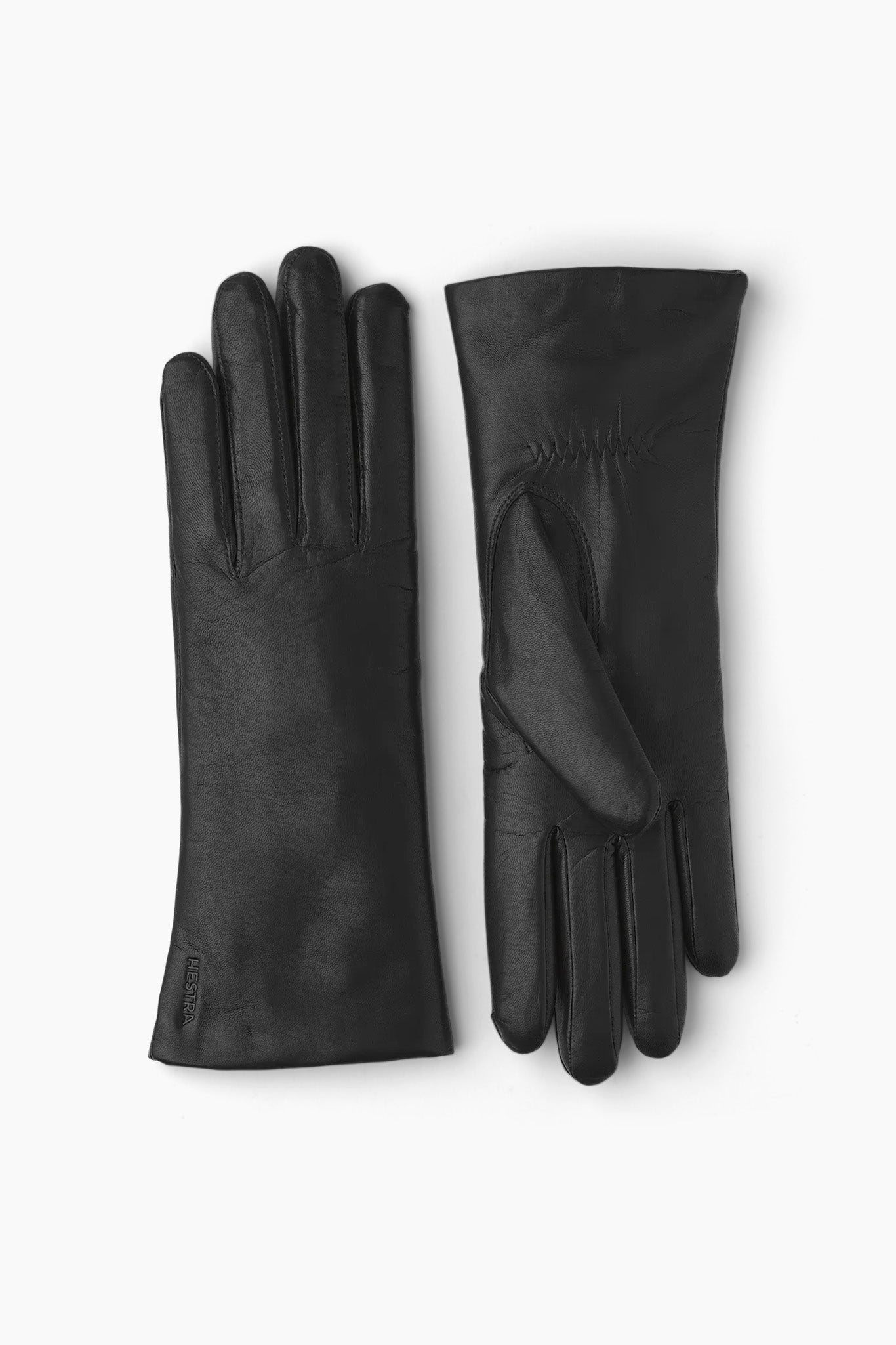 Women's black leather gloves laying flat on a grey background