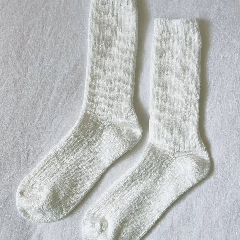 White cotton cozy ribbed cottage socks on a flat white sheet