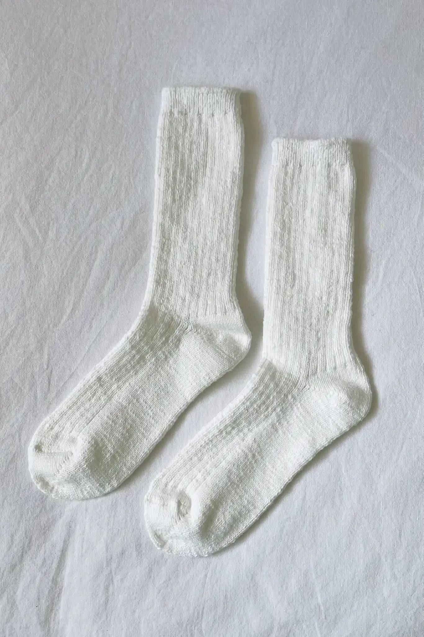 White cotton cozy ribbed cottage socks on a flat white sheet