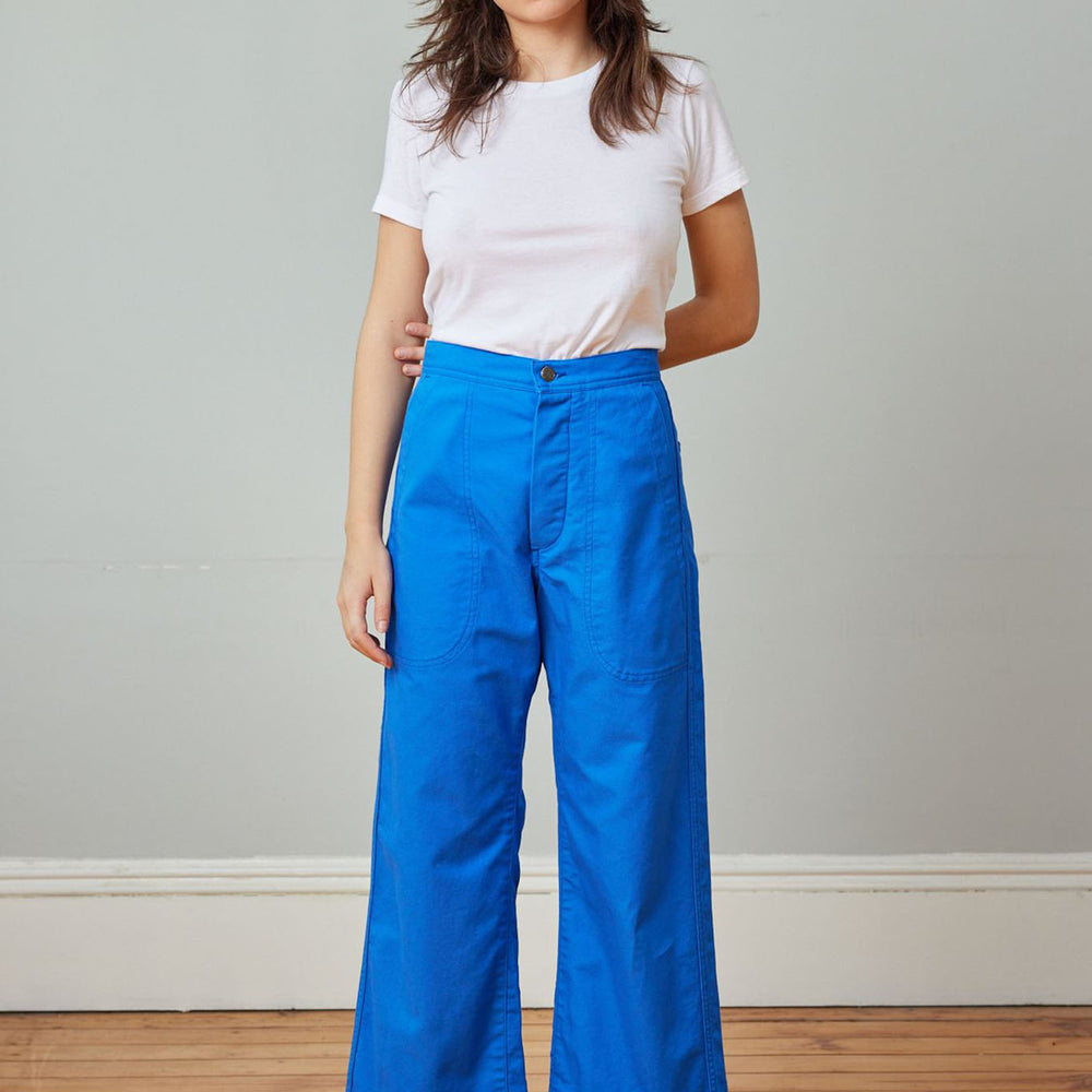 A person standing wearing a white t-shirt and cobalt blue high-rise wide-leg crop sailor pant with front pockets.