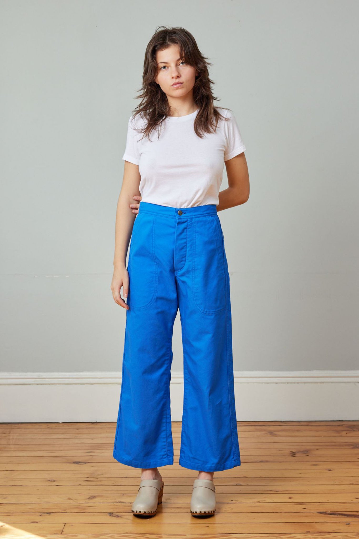A person standing wearing a white t-shirt and cobalt blue high-rise wide-leg crop sailor pant with front pockets.